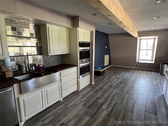 514 Lakeshore St, Durant, OK 74701 - kitchen with stainless steel appliances, a textured ceiling, tasteful backsplash, dark wood-type flooring, and white cabinets