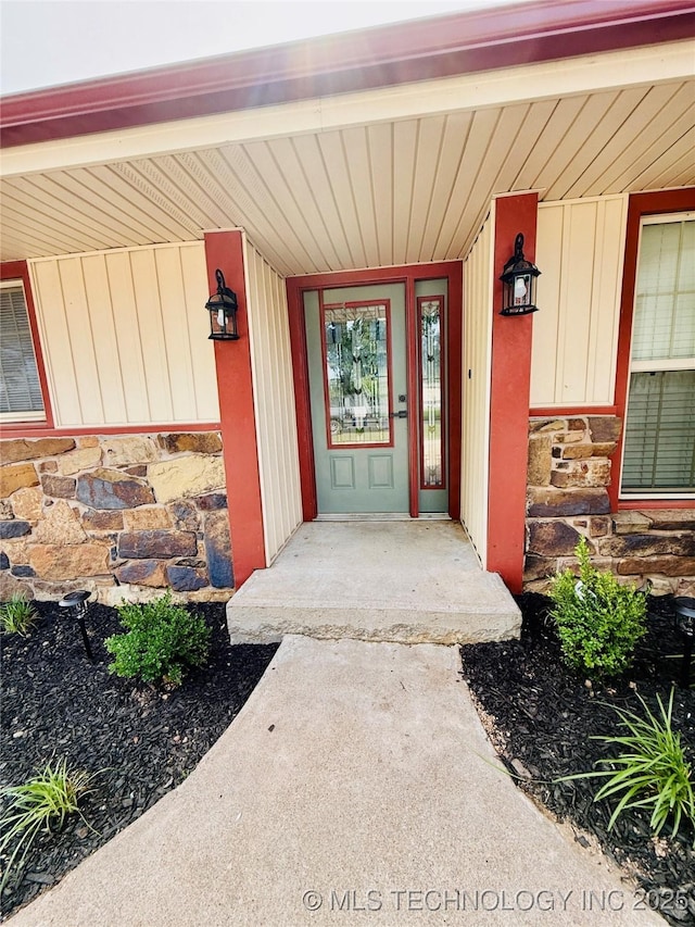 doorway to property with stone siding and a porch