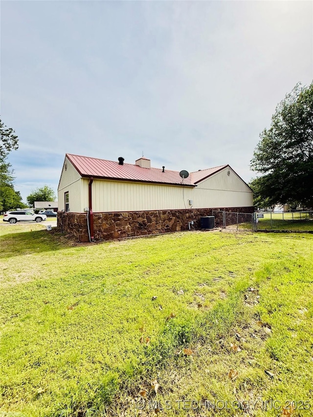 view of side of home featuring stone siding, metal roof, and central AC