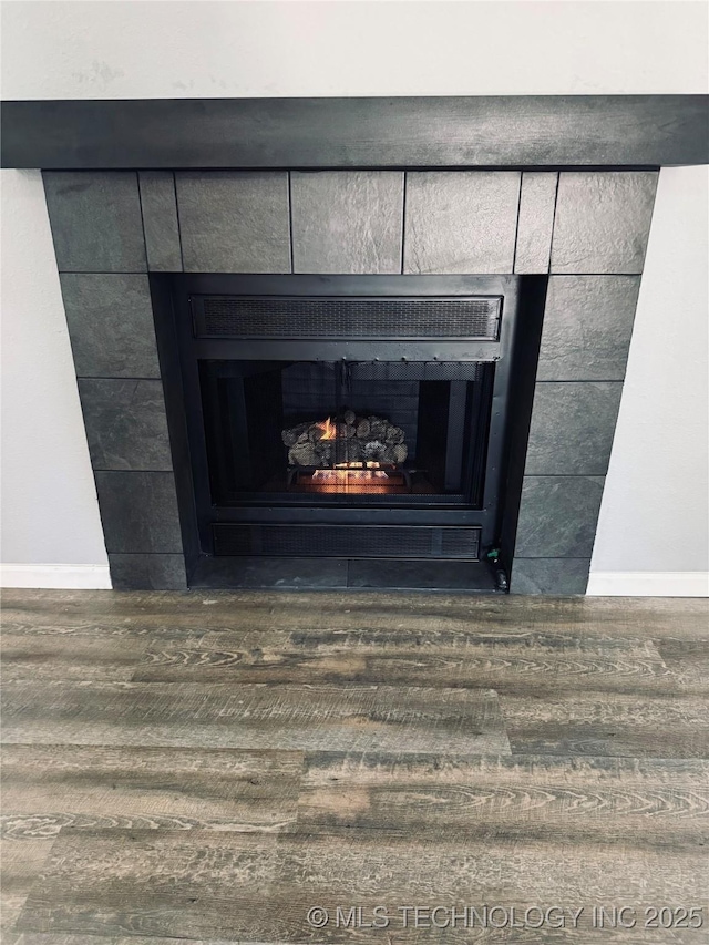 detailed view of wood finished floors, baseboards, and a tile fireplace