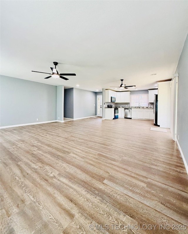 unfurnished living room featuring a ceiling fan, light wood-style floors, and baseboards