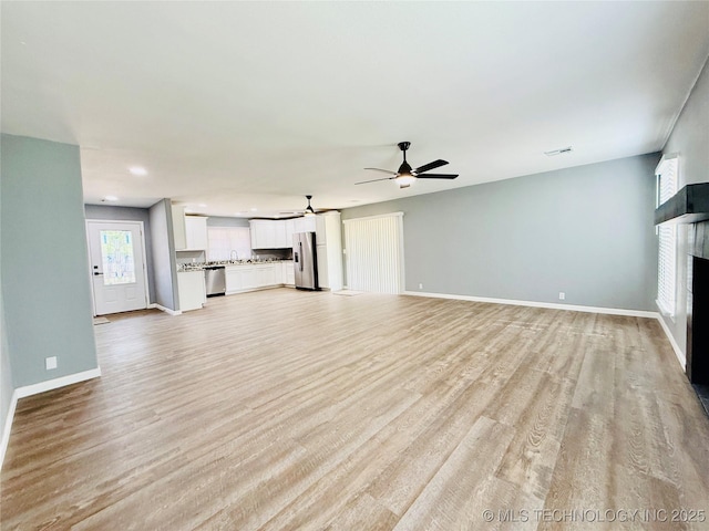 unfurnished living room with a fireplace, a ceiling fan, baseboards, light wood finished floors, and recessed lighting