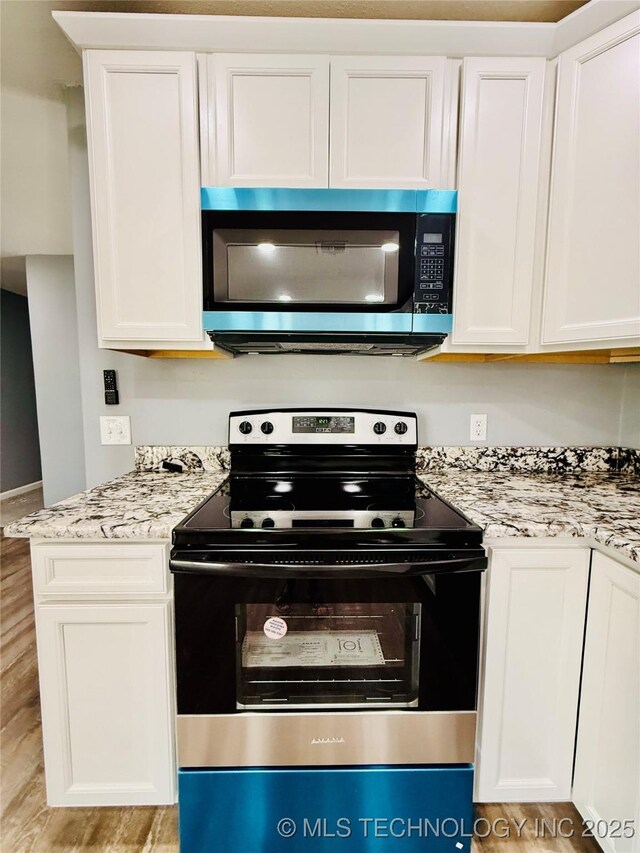 kitchen with electric stove, white cabinets, light wood finished floors, and light stone counters