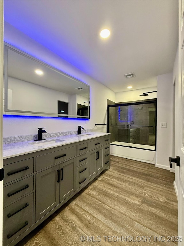 bathroom with a shower stall, double vanity, wood finished floors, and recessed lighting