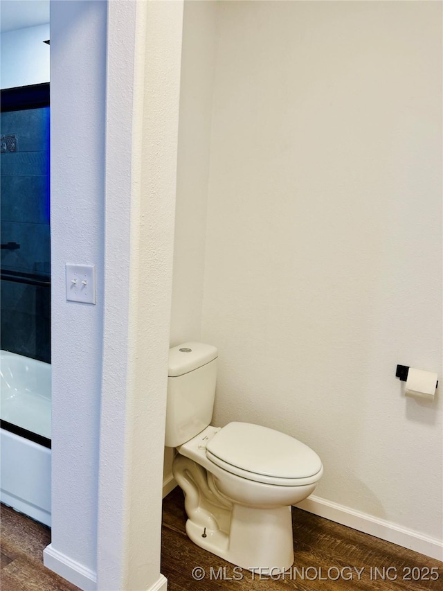 bathroom with toilet, baseboards, and wood finished floors