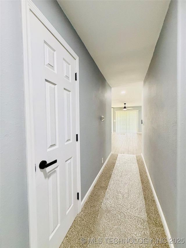 hallway with carpet floors and baseboards