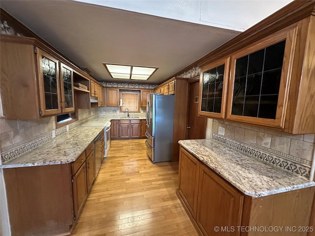 924 9th Ave SE, Ardmore, OK 73401 - kitchen featuring freestanding refrigerator, a sink, light wood-type flooring, and backsplash