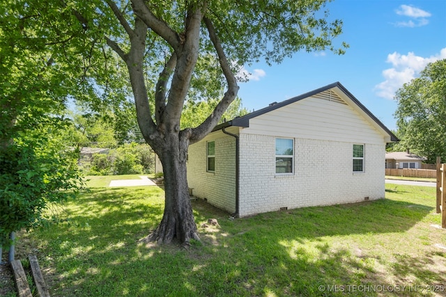view of home's exterior with brick siding, crawl space, and a lawn