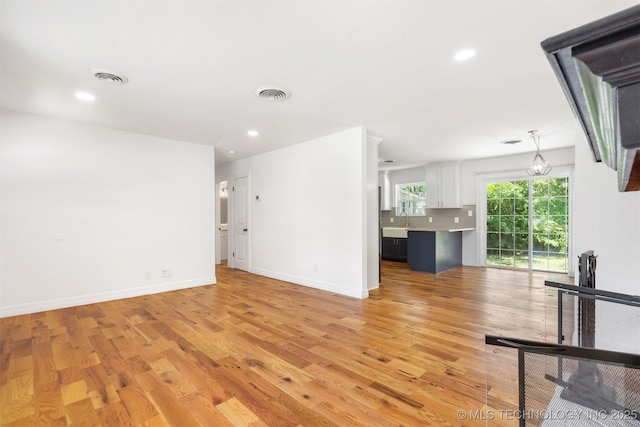 unfurnished living room with light wood-style floors, baseboards, recessed lighting, and a sink