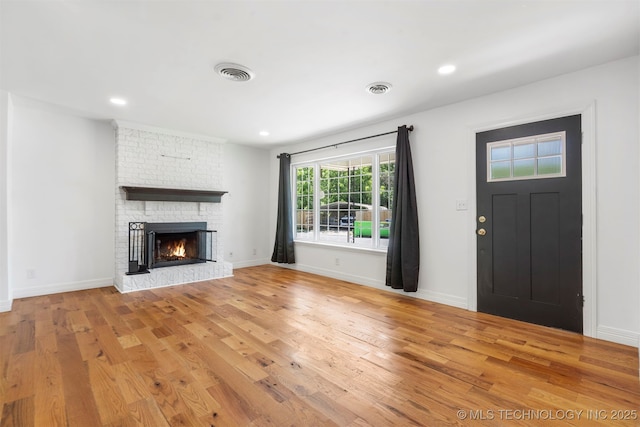 unfurnished living room with light wood-style floors, a fireplace, baseboards, and recessed lighting