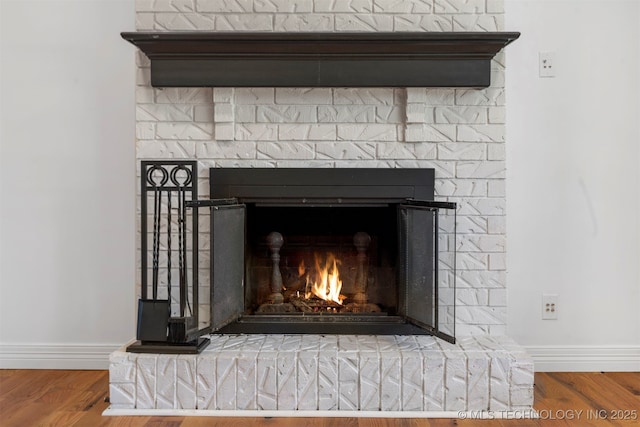 detailed view of a fireplace, baseboards, and wood finished floors
