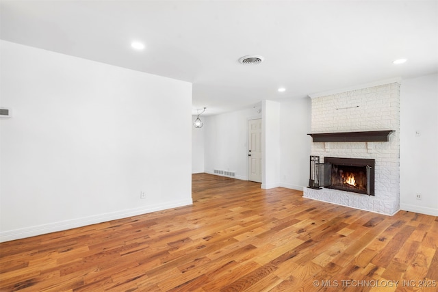 unfurnished living room with light wood-type flooring, a fireplace, baseboards, and recessed lighting