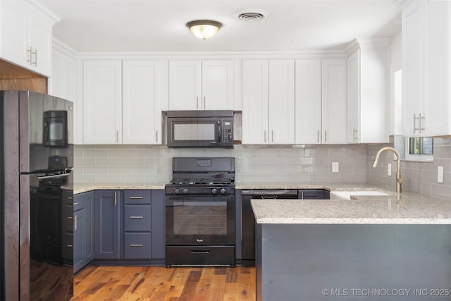 kitchen with black appliances, a sink, white cabinetry, a peninsula, and decorative backsplash