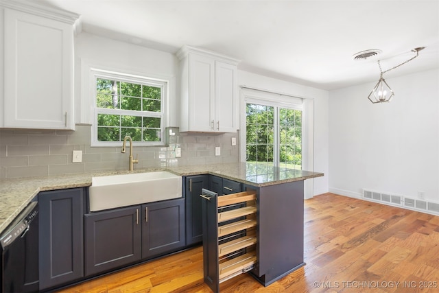 kitchen featuring a sink, white cabinetry, black dishwasher, and backsplash