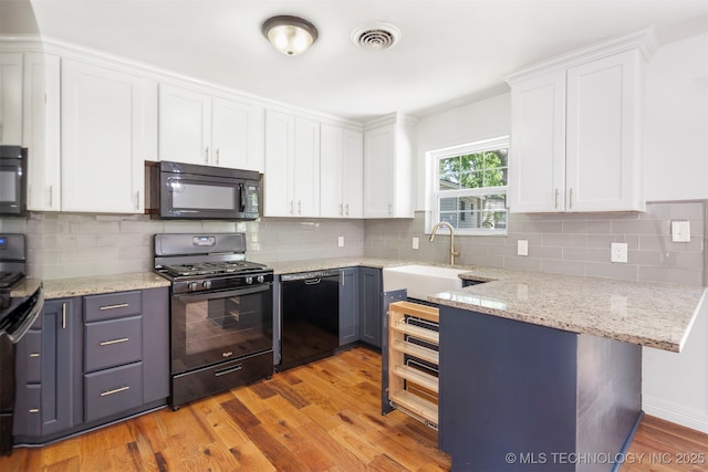 kitchen with black appliances, a sink, white cabinetry, light wood finished floors, and backsplash