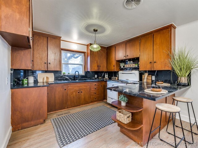 2528 E 57th St, Tulsa, OK 74105 - kitchen featuring white gas range oven, open shelves, brown cabinets, light wood-style flooring, and a peninsula