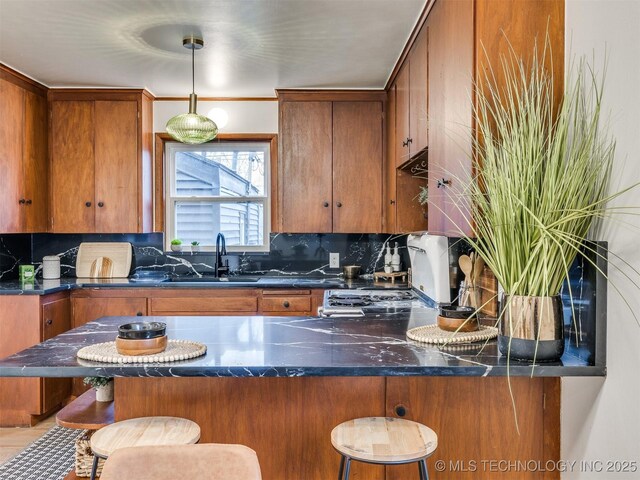2528 E 57th St, Tulsa, OK 74105 - kitchen with a sink, brown cabinetry, tasteful backsplash, and a breakfast bar area