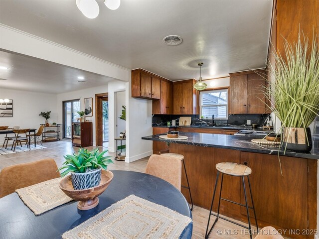 2528 E 57th St, Tulsa, OK 74105 - kitchen with brown cabinetry, tasteful backsplash, a peninsula, and a sink
