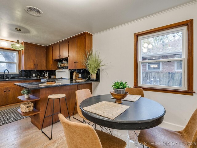 2528 E 57th St, Tulsa, OK 74105 - kitchen featuring light wood-style flooring, tasteful backsplash, open shelves, a peninsula, and brown cabinetry