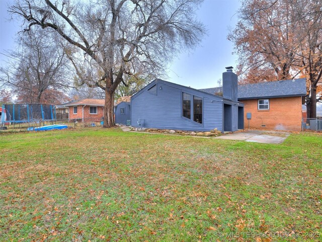 2528 E 57th St, Tulsa, OK 74105 - rear view of house with a trampoline, a chimney, brick siding, and a patio