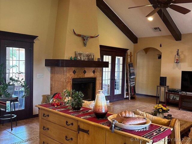 1216 N Oak Grove Rd, Drumright, OK 74030 - living room with arched walkways, beamed ceiling, ceiling fan, a tile fireplace, and light tile patterned flooring
