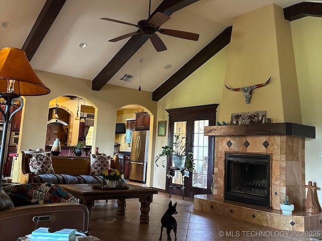 1216 N Oak Grove Rd, Drumright, OK 74030 - tiled living room featuring a ceiling fan, beam ceiling, plenty of natural light, arched walkways, and a tiled fireplace