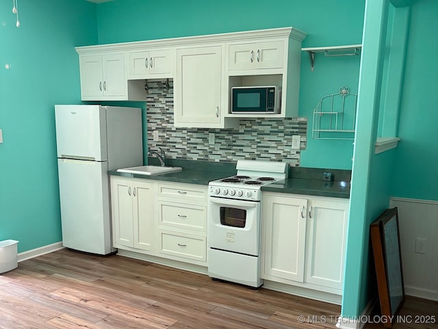 1216 N Oak Grove Rd, Drumright, OK 74030 - kitchen featuring white appliances, a sink, dark countertops, tasteful backsplash, and light wood-style floors