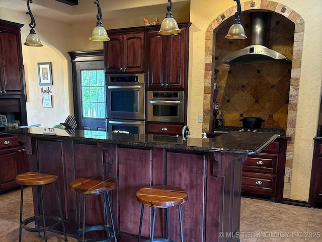 1216 N Oak Grove Rd, Drumright, OK 74030 - kitchen featuring reddish brown cabinets, a textured wall, double oven, a kitchen breakfast bar, and light tile patterned flooring
