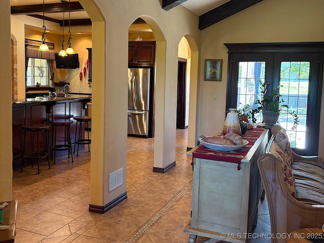 1216 N Oak Grove Rd, Drumright, OK 74030 - kitchen with stainless steel fridge, beamed ceiling, arched walkways, light tile patterned floors, and a kitchen breakfast bar