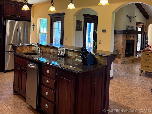 1216 N Oak Grove Rd, Drumright, OK 74030 - kitchen with a sink, freestanding refrigerator, a fireplace, arched walkways, and healthy amount of natural light