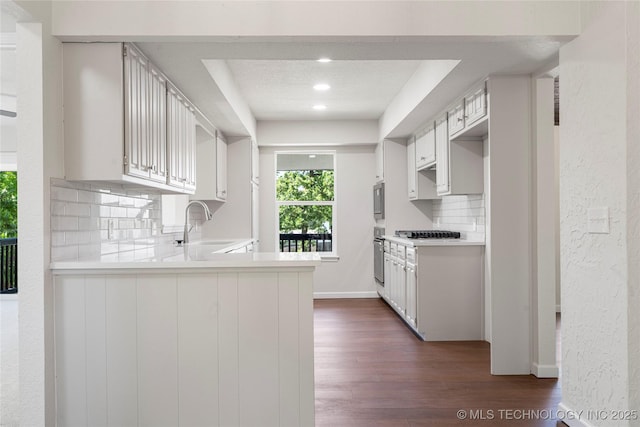 3442 E 75th Pl, Tulsa, OK 74136 - kitchen featuring tasteful backsplash, dark wood finished floors, stainless steel appliances, a sink, and a peninsula