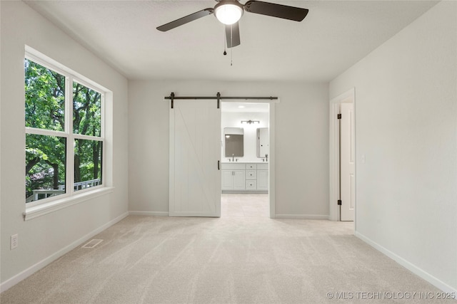 3442 E 75th Pl, Tulsa, OK 74136 - empty room with ceiling fan, light colored carpet, a barn door, and baseboards