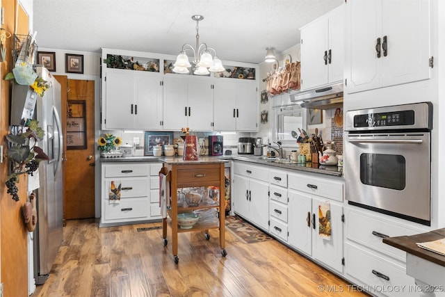 819 W Elm St, Durant, OK 74701 - kitchen with stainless steel appliances, a chandelier, a textured ceiling, and white cabinetry