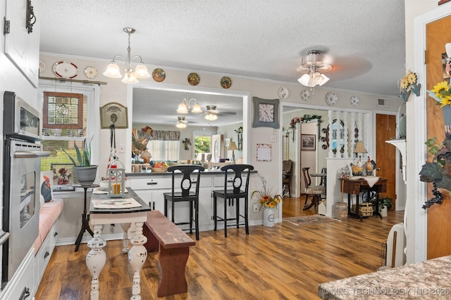 819 W Elm St, Durant, OK 74701 - dining area featuring a ceiling fan, a chandelier, a textured ceiling, crown molding, and wood finished floors