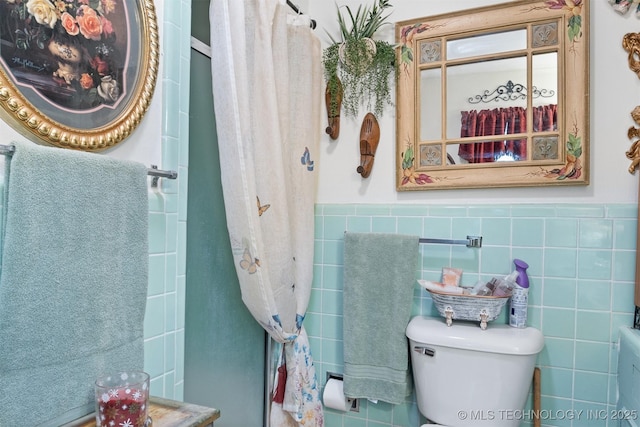 819 W Elm St, Durant, OK 74701 - bathroom with a wainscoted wall, tile walls, toilet, and curtained shower