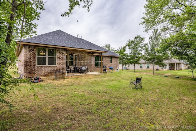 71 Rebel Ln, Durant, OK 74701 - back of property with brick siding, a shingled roof, a patio area, and a lawn