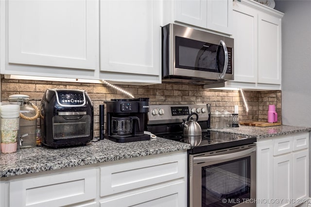71 Rebel Ln, Durant, OK 74701 - kitchen with appliances with stainless steel finishes, decorative backsplash, white cabinets, and light stone countertops