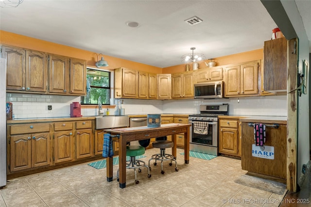 10797 S Talala Creek Ct # B, Talala, OK 74080 - kitchen with stainless steel appliances, decorative backsplash, a chandelier, and brown cabinets