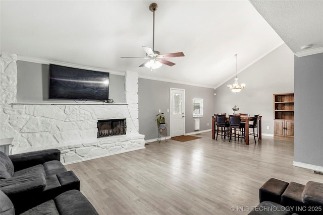 living room with a stone fireplace, ceiling fan, crown molding, wood finished floors, and baseboards