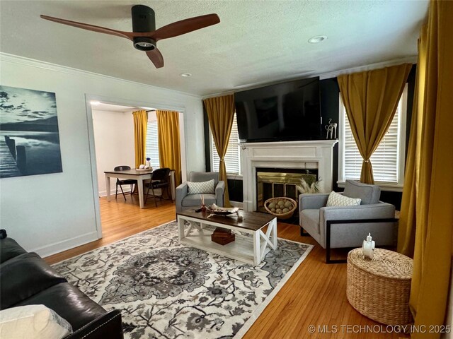 2009 S Osage Ave, Bartlesville, OK 74006 - living area with a ceiling fan, ornamental molding, a fireplace, light wood-style flooring, and baseboards