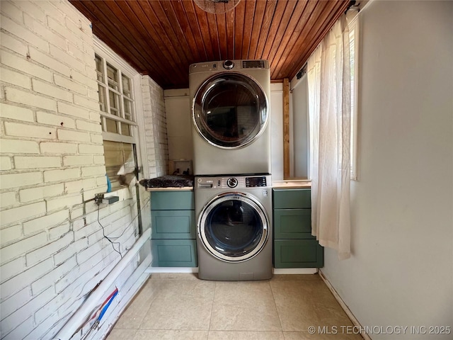 2009 S Osage Ave, Bartlesville, OK 74006 - laundry area featuring stacked washer / dryer, cabinet space, wood ceiling, light tile patterned floors, and baseboards