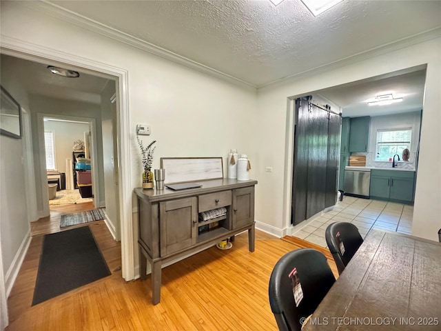 2009 S Osage Ave, Bartlesville, OK 74006 - home office featuring light wood-type flooring, baseboards, crown molding, a sink, and a textured ceiling