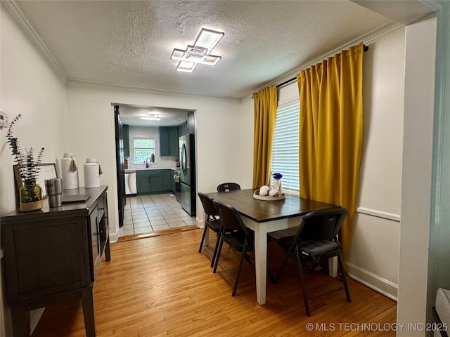 2009 S Osage Ave, Bartlesville, OK 74006 - dining room with light wood-style flooring, a textured ceiling, crown molding, and baseboards