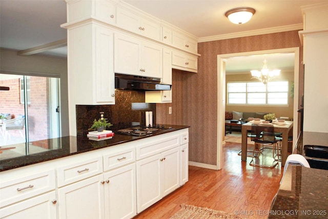 4507 S Irvington Ave, Tulsa, OK 74135 - kitchen with under cabinet range hood, wallpapered walls, black electric stovetop, light wood-type flooring, and white cabinets