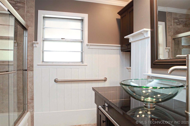 4507 S Irvington Ave, Tulsa, OK 74135 - full bathroom featuring crown molding, wainscoting, a sink, and shower / bath combination with glass door
