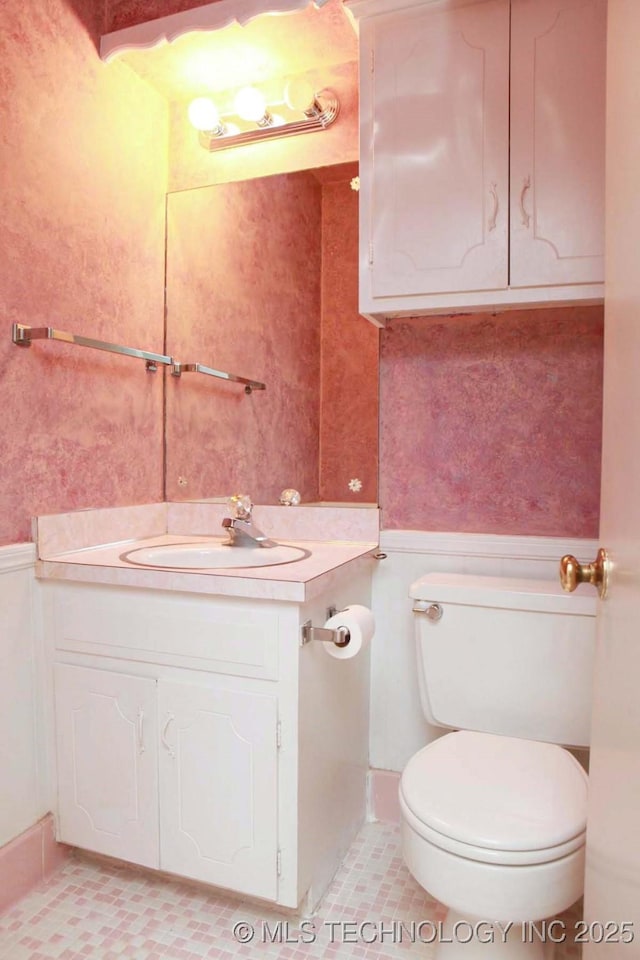 4507 S Irvington Ave, Tulsa, OK 74135 - half bath with a wainscoted wall, toilet, vanity, and tile patterned flooring