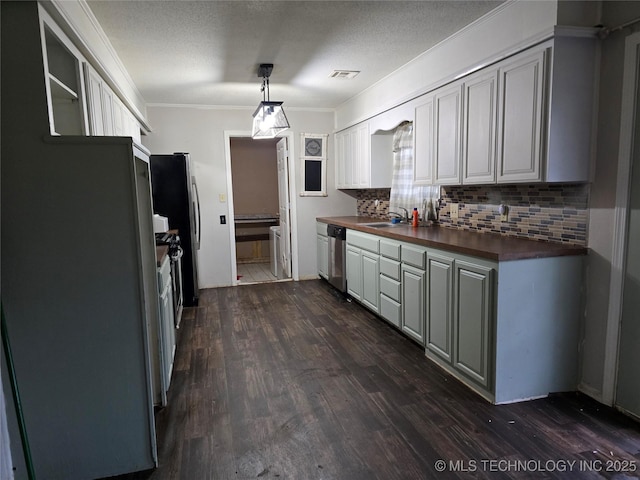 309 Hillcrest St, Pawnee, OK 74058 - kitchen with butcher block counters, stainless steel appliances, dark wood-style floors, decorative backsplash, and crown molding