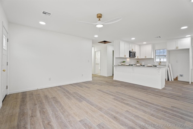 3919 E Archer St, Tulsa, OK 74115 - kitchen featuring stainless steel microwave, white cabinetry, light wood-style flooring, ceiling fan, and recessed lighting