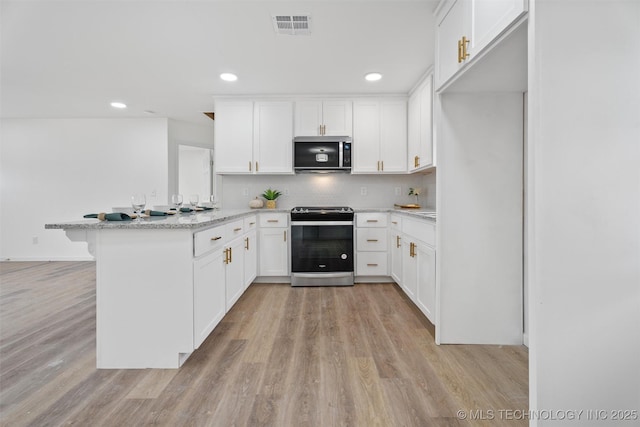 3919 E Archer St, Tulsa, OK 74115 - kitchen featuring stainless steel appliances, a peninsula, light wood-type flooring, white cabinetry, and tasteful backsplash