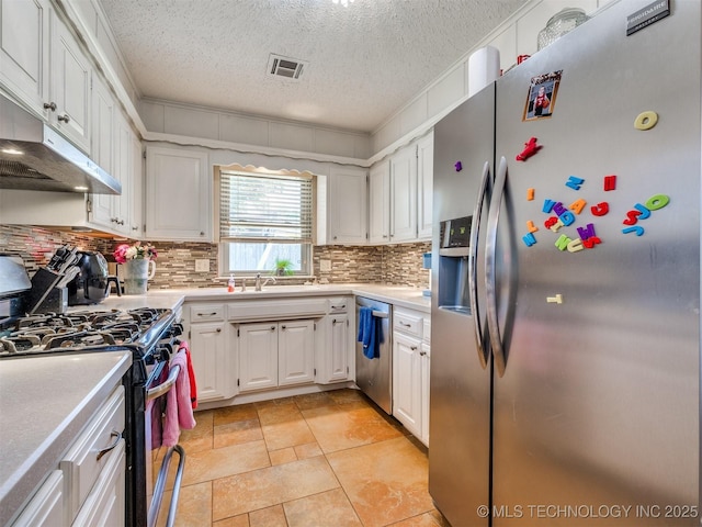 124 Canterbury Ct, Bartlesville, OK 74006 - kitchen featuring appliances with stainless steel finishes, light countertops, decorative backsplash, white cabinets, and a textured ceiling
